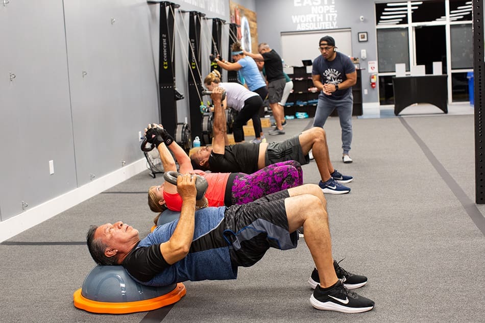 Coastal Fitness members doing KB straight arm pullovers during a group training session