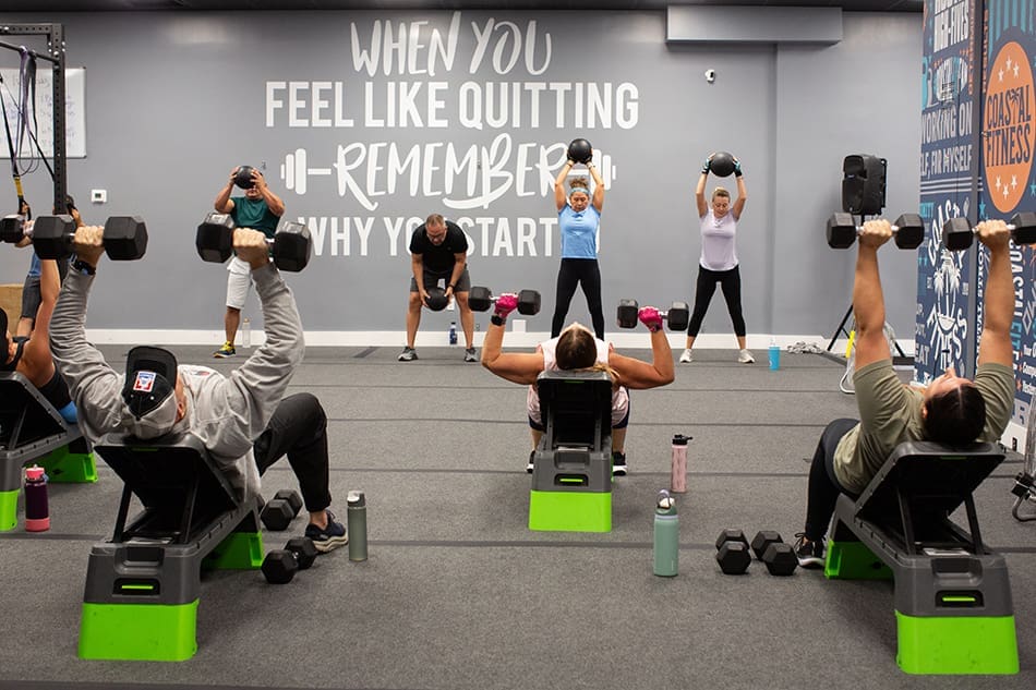 Group personal training class, members working out at Coastal Fitness bench pressing